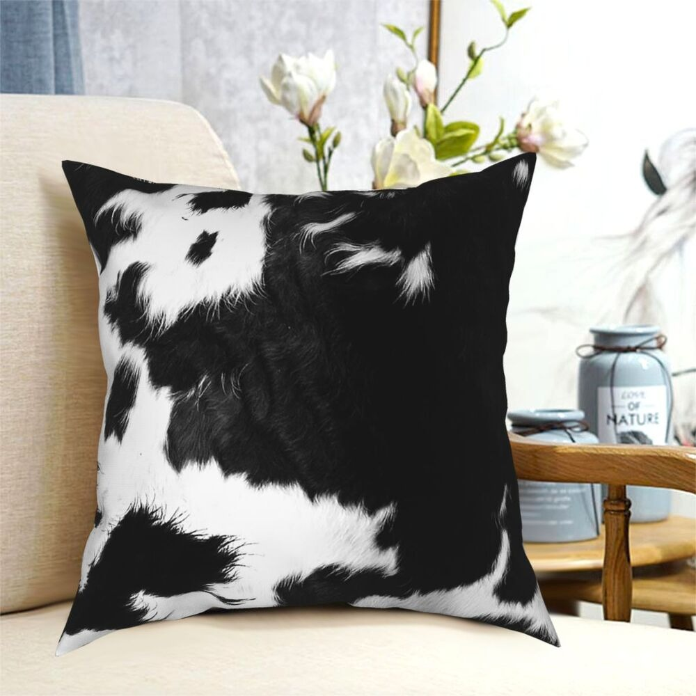 Modern black and white cowhide pillow on sofa, stylish home decor, perfect gift with trendy cow print.