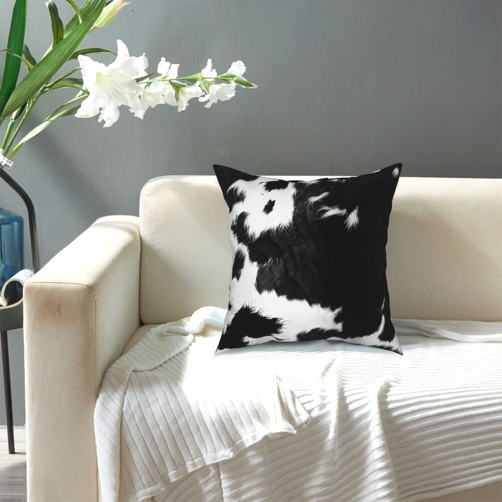 Modern black and white cowhide pillow on a cozy sofa, perfect for trendy home decor and gifts.