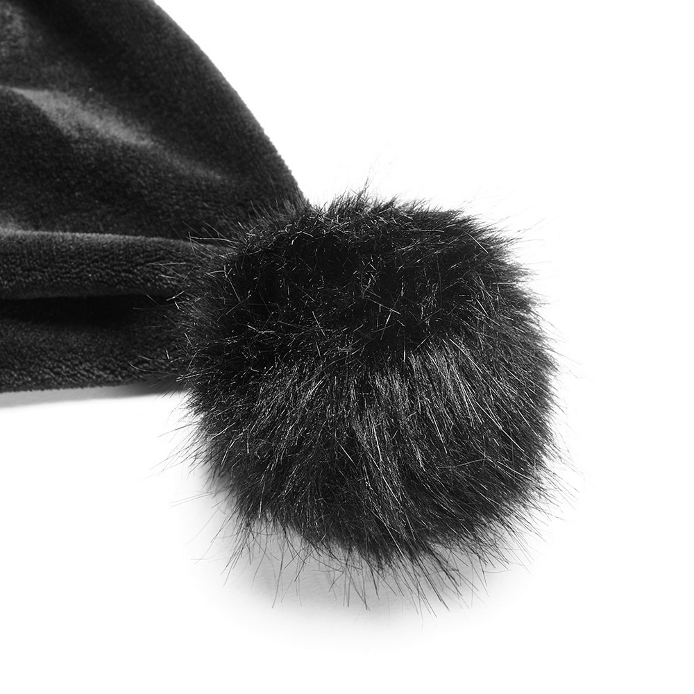 Close-up of a fluffy black pom pom on a dark velvet cloak, adding a stylish touch to cozy outerwear.