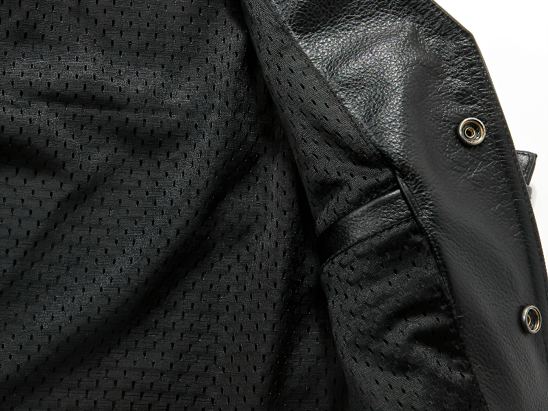 Close-up of interior lining of a black leather vest showing breathable fabric and stylish details.
