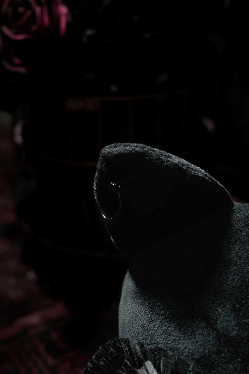 Close-up of a gothic black cat plush with a lace collar and a whimsical ear detail, set against a dark, moody background.