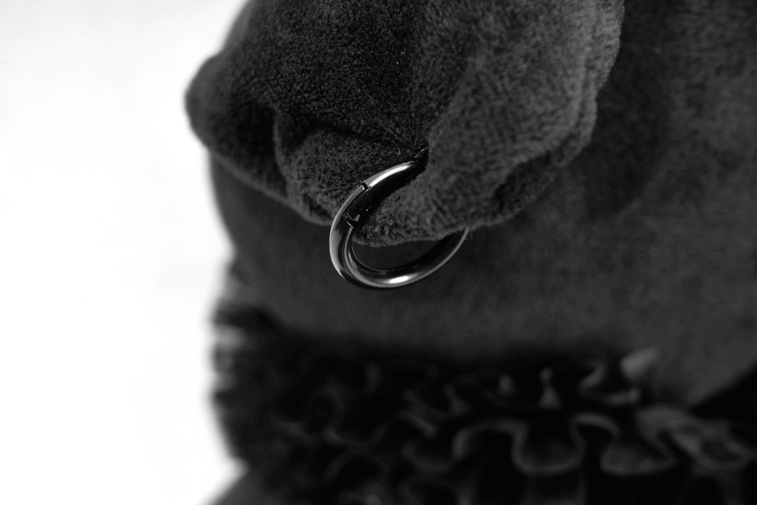 Close-up of a black cat toy's plush ear featuring a detachable collar ring.