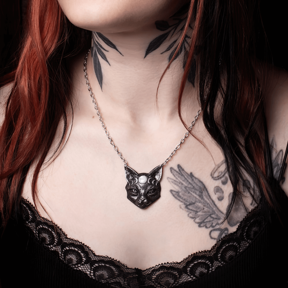 Mystic Moon Cat Pendant with black cat design and moon phases, worn by a model with tattoos, showcasing feminine magic.