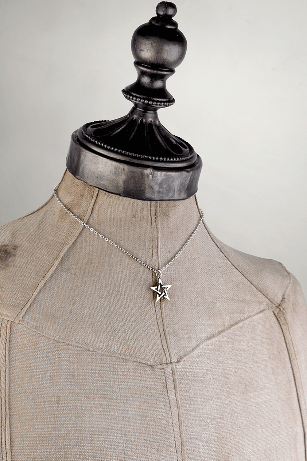 Mystical pentagram pendant displayed on a vintage mannequin, symbolizes elemental forces and cosmic balance.