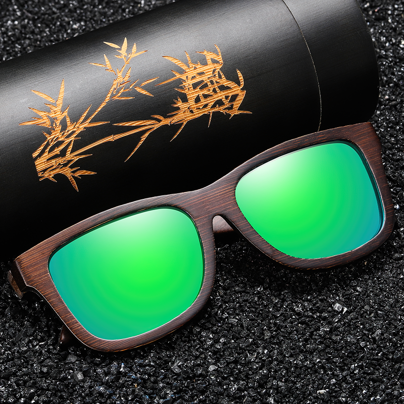 Handmade bamboo wooden sunglasses with green polarized lenses placed on a decorative gift box.