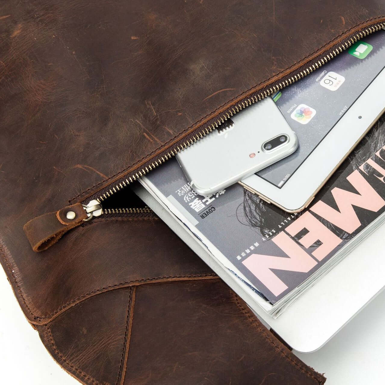 Genuine leather backpack showing an interior with a phone, tablet, and magazines, perfect for travel and daily use.