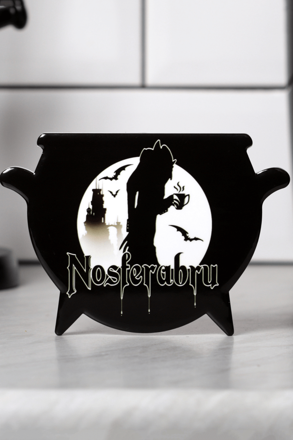 Nosferabru vampire cauldron coaster with a haunting silhouette of a vampire sipping tea and bats.