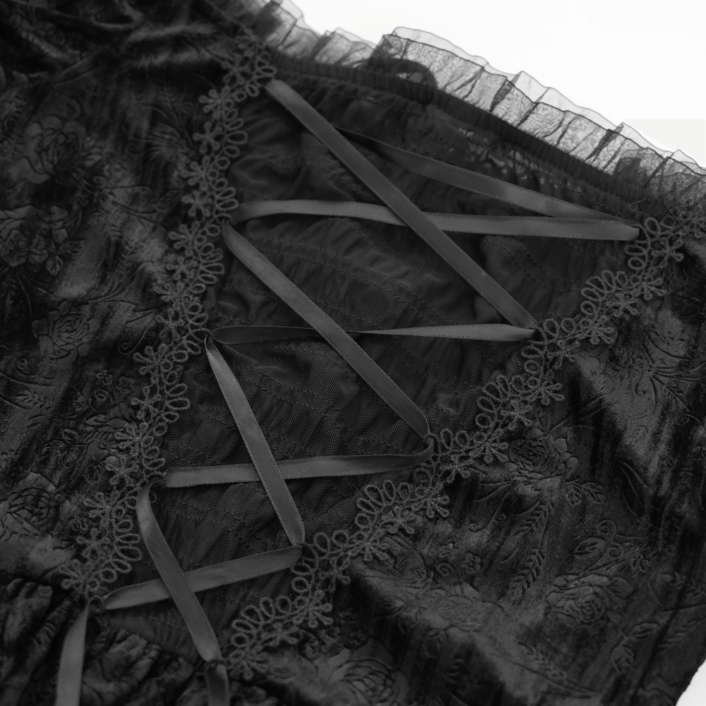 Close-up of lace-up detailing on a black velvet top with sheer fabric and intricate lace trim.