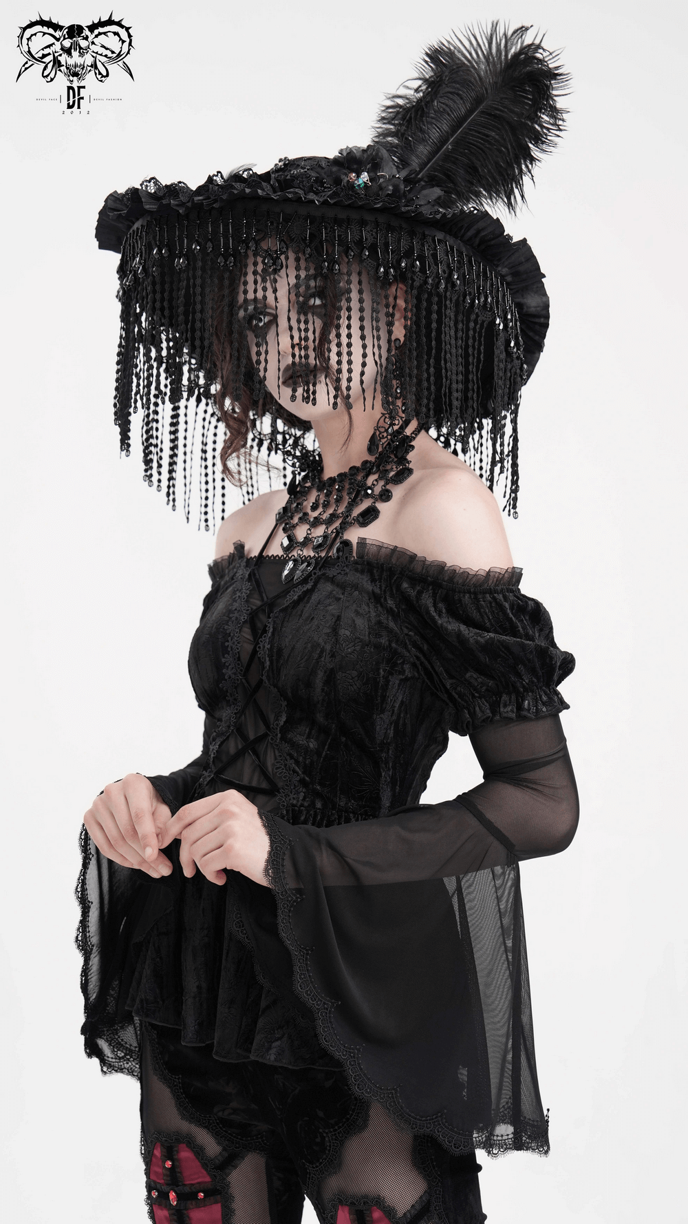 Gothic elegance: Off-shoulder velvet top with sheer sleeves and lace trim, paired with a dramatic hat and dark accessories.