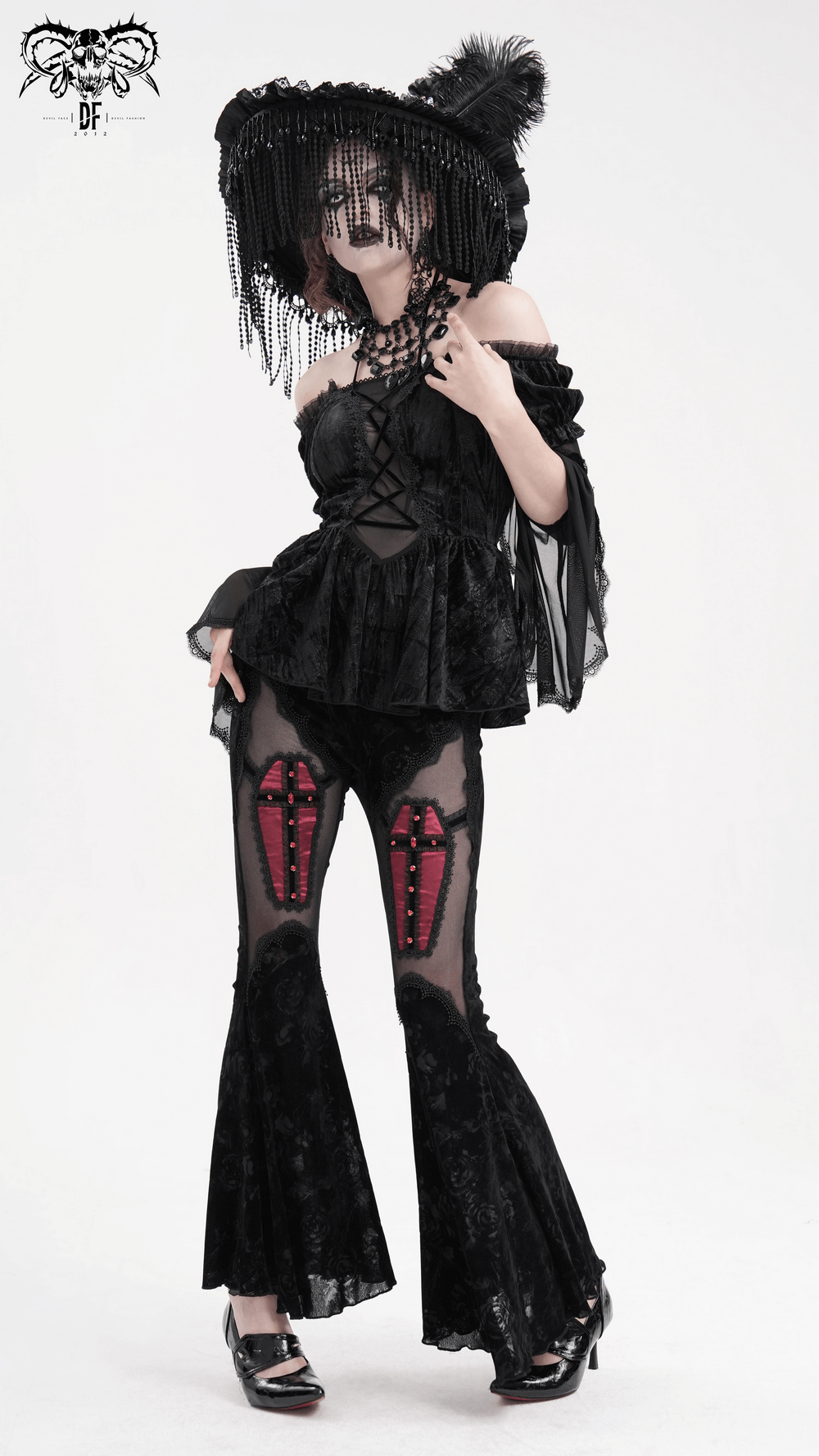 Gothic fashion model in off-shoulder velvet top with sheer sleeves and lace trim, flared bell-bottoms, and dramatic hat.