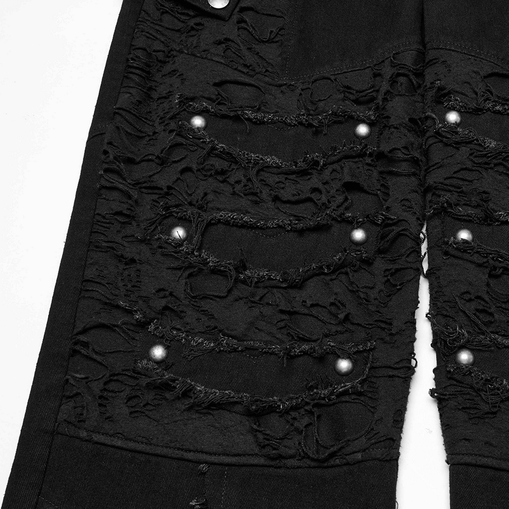 Close-up of black punk pants featuring distressed mesh, ripped detail, and silver studs for edgy style.
