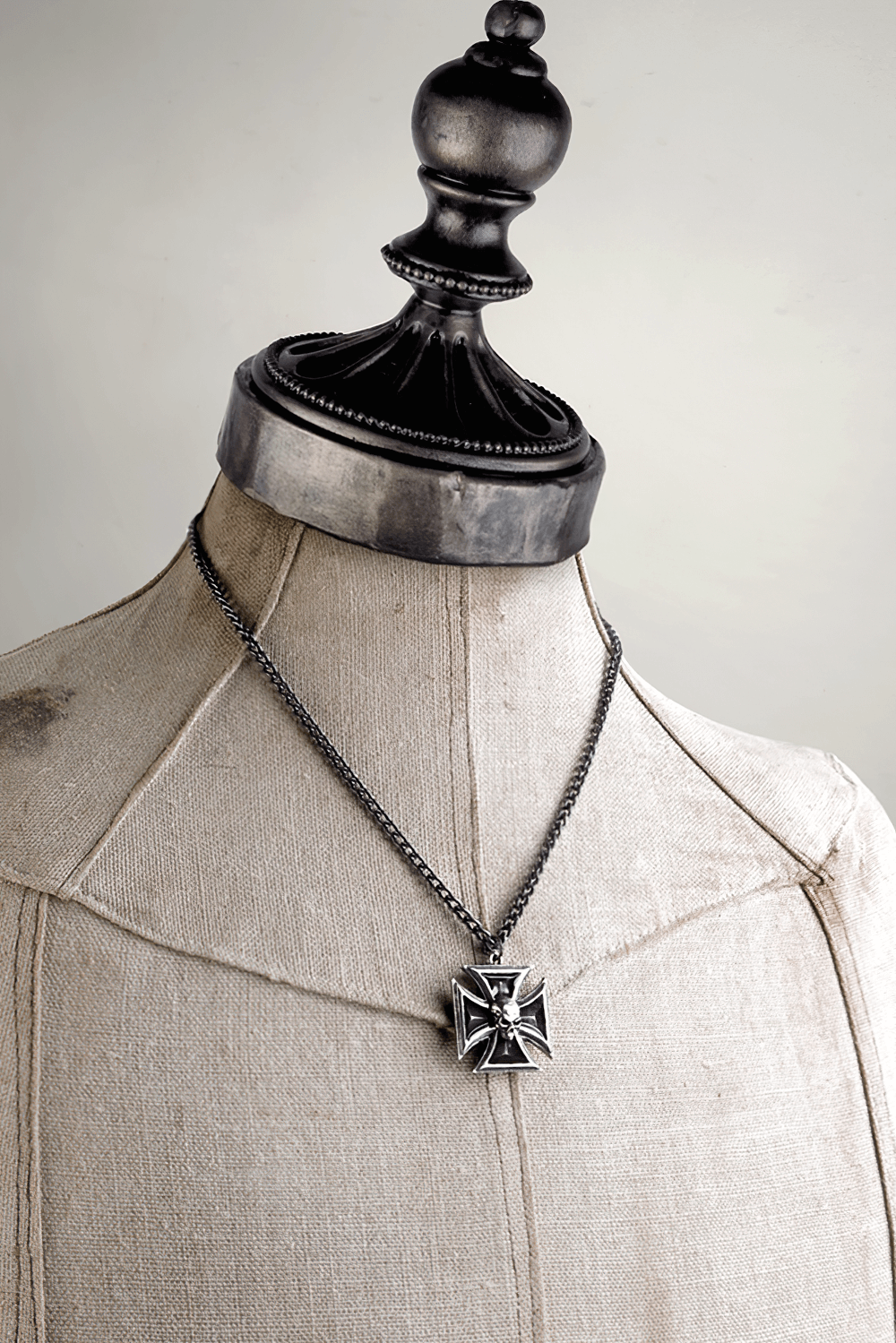 Pewter Iron Cross pendant with detailed skull and black enamel, showcased on a mannequin.