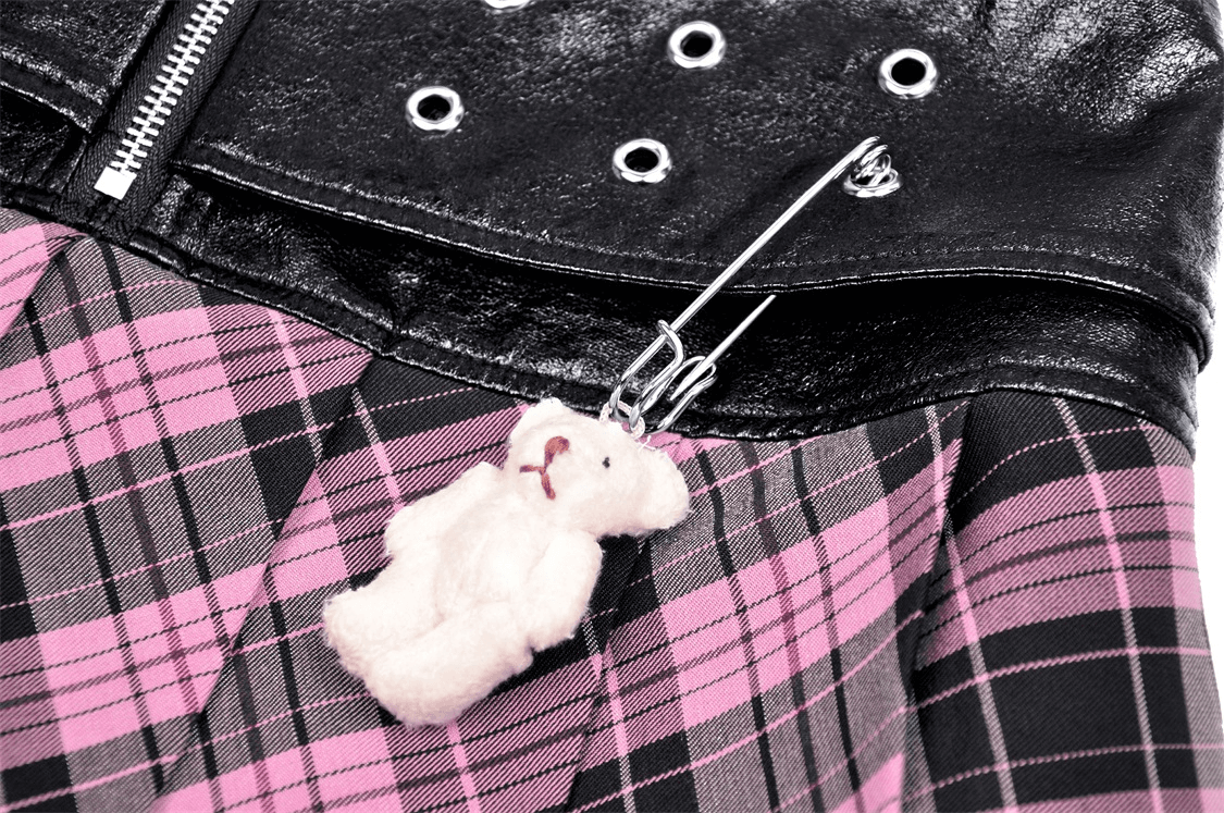 Close-up of pink plaid mini skirt with edgy leather, featuring a teddy bear charm and metal grommet details.