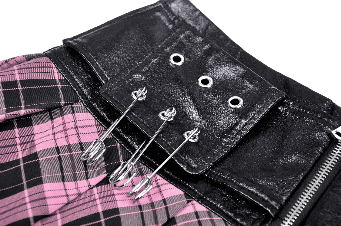 Close-up of pink and black plaid skirt with edgy leather belt featuring grommet detail and safety pins.