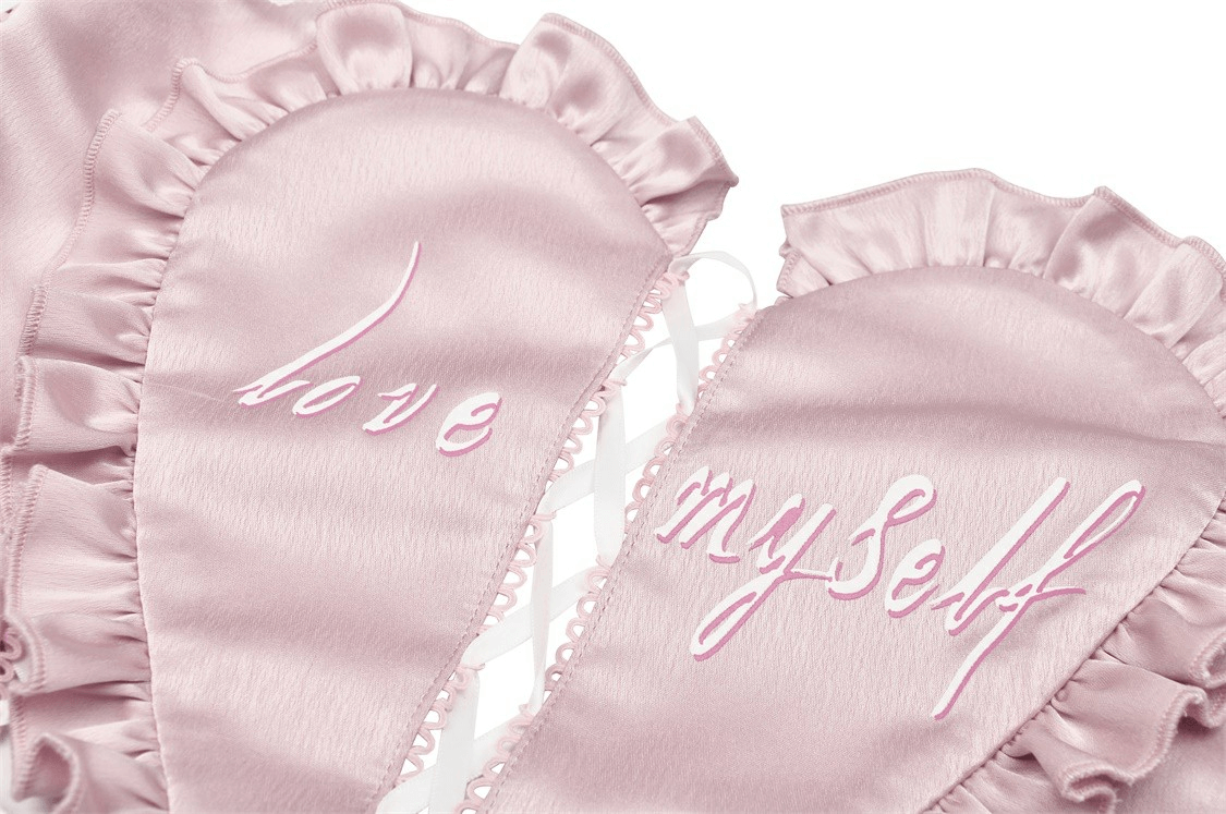 Pink satin sleep mask with ruffled edges, featuring embroidered text 'love myself' in playful cursive.