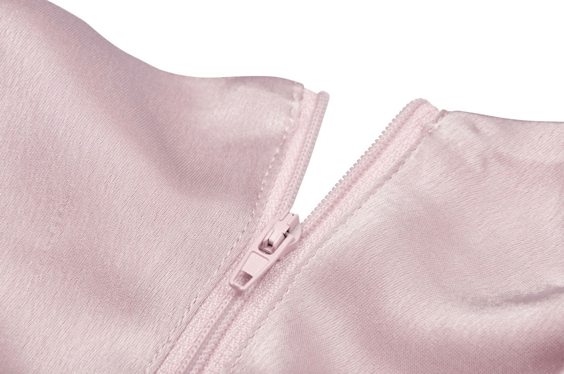 Close-up of pink heart-shaped bustier top zipper detail, showcasing sleek satin finish and lace-up design.