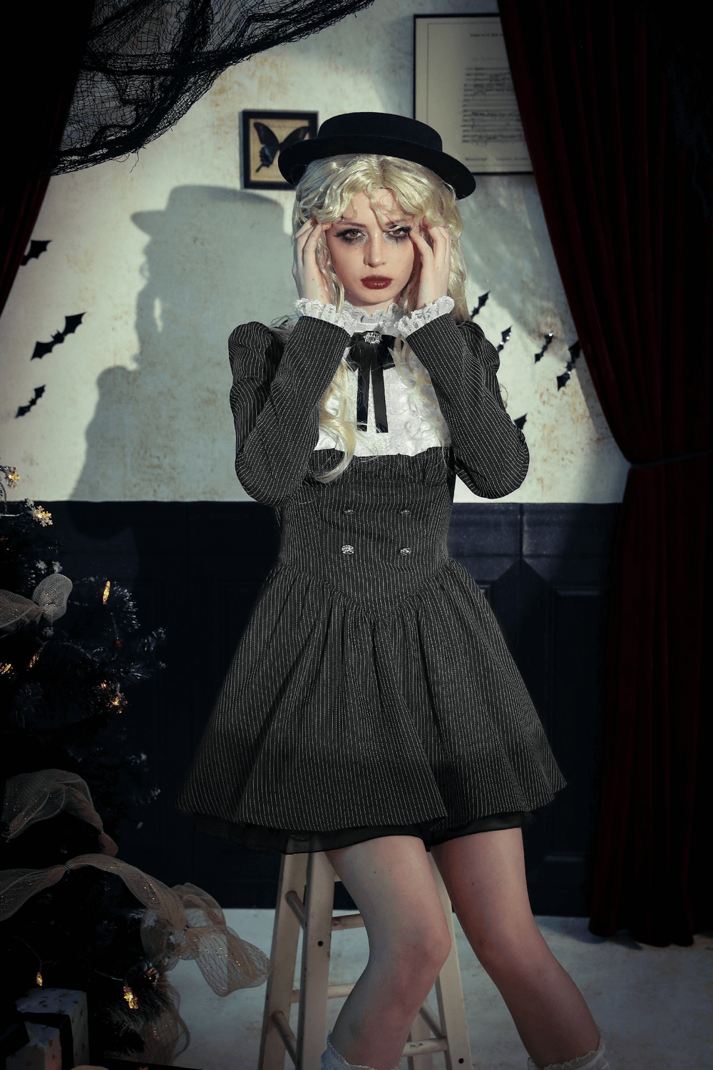 Stylish model in a pinstripe gothic dress with lace ruffle and bow, showcasing vintage charm in an elegant setting.