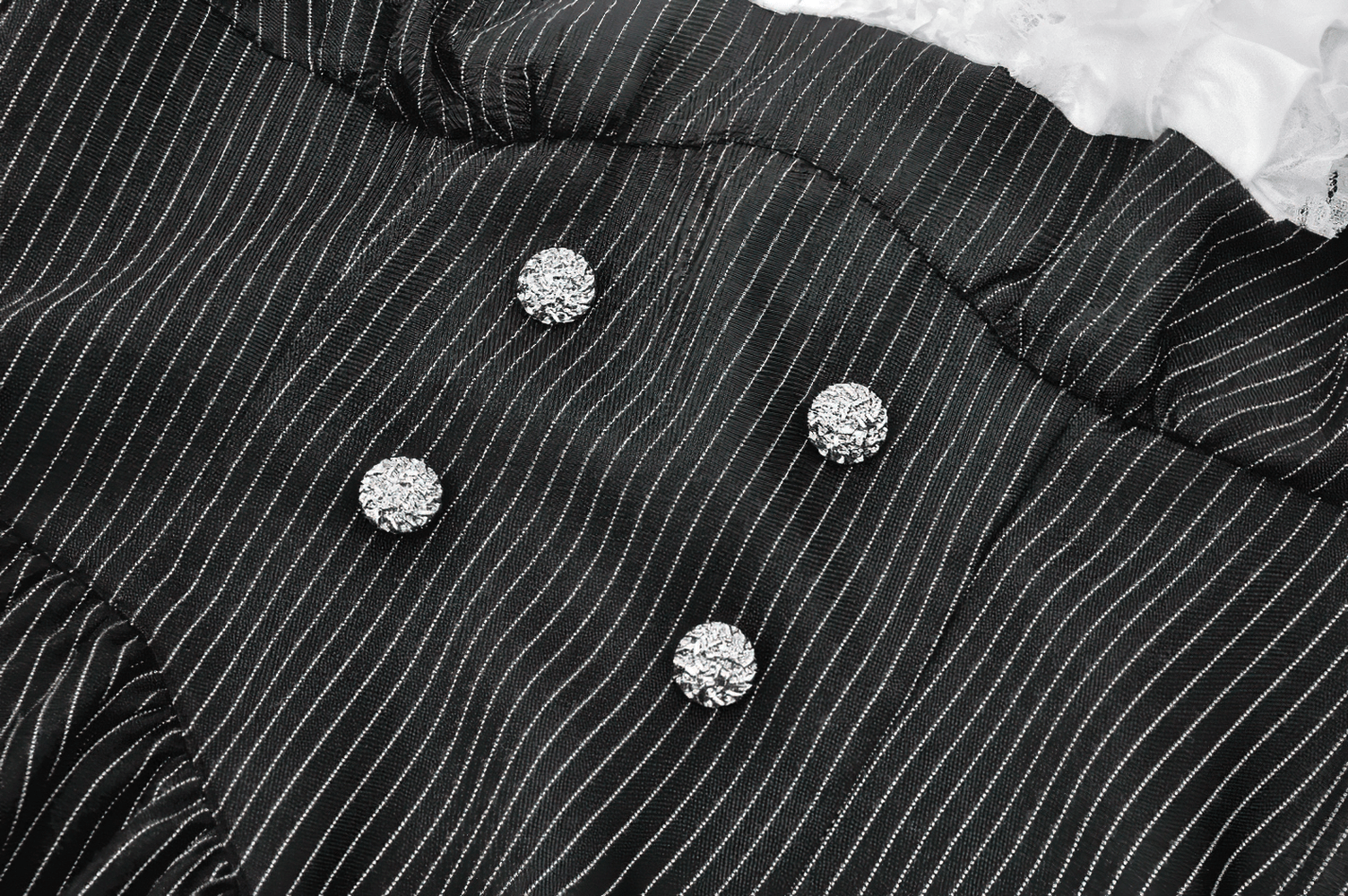 Close-up of double-breasted rhinestone buttons on a gothic pinstripe dress with lace ruffle detail.