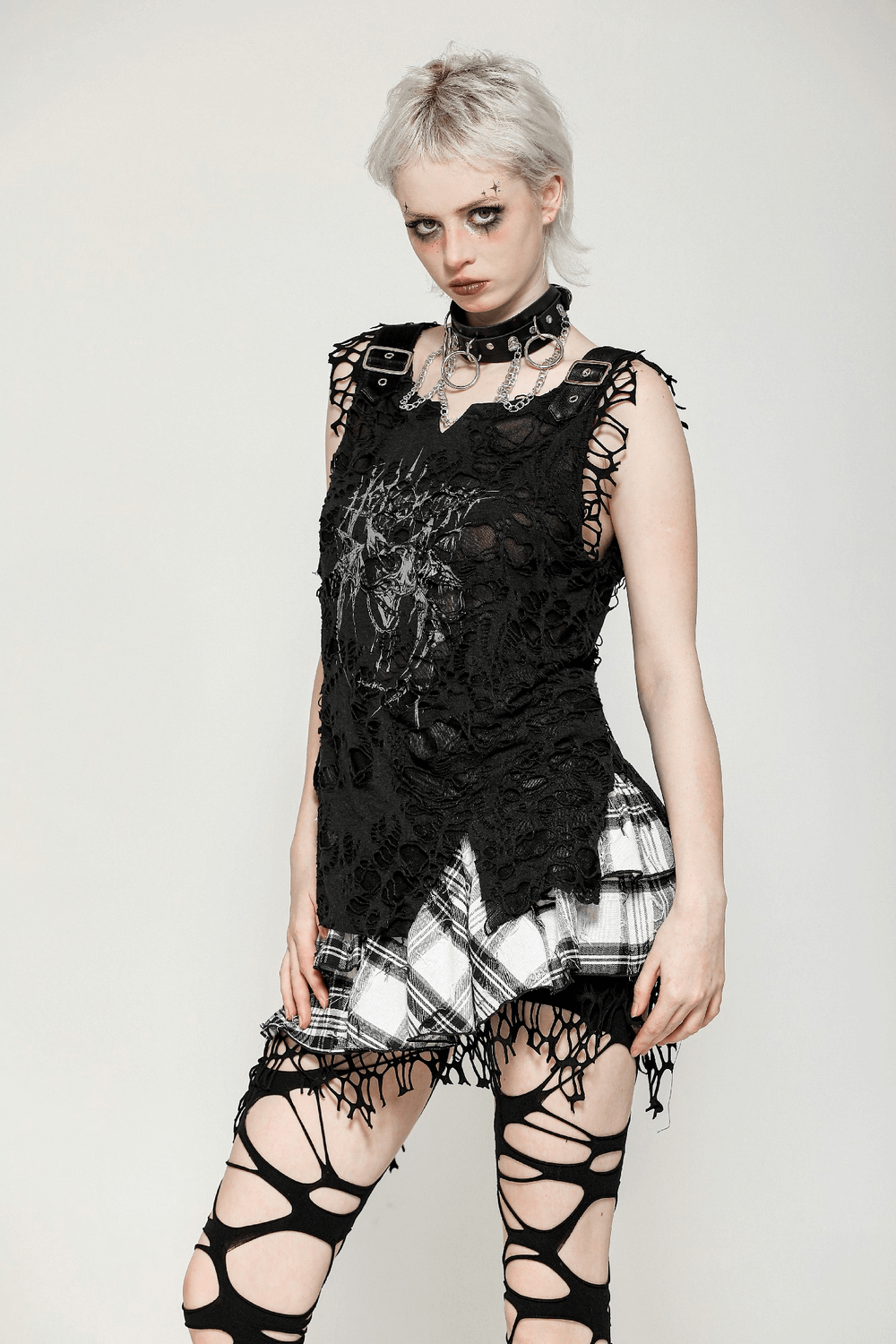 Gothic model in layered black ruffled outfit with plaid, mesh trim, and edgy cut-outs, showcasing alternative fashion style.