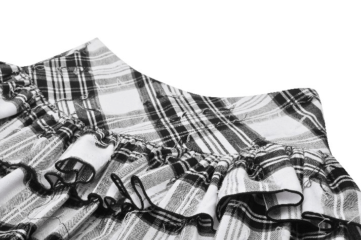 Close-up of the ruffled top of a plaid layered mini skirt with mesh trim and black accents.