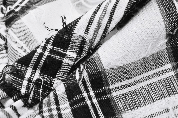 Close-up of black and white plaid fabric with frayed edges, perfect for gothic and alternative fashion designs.