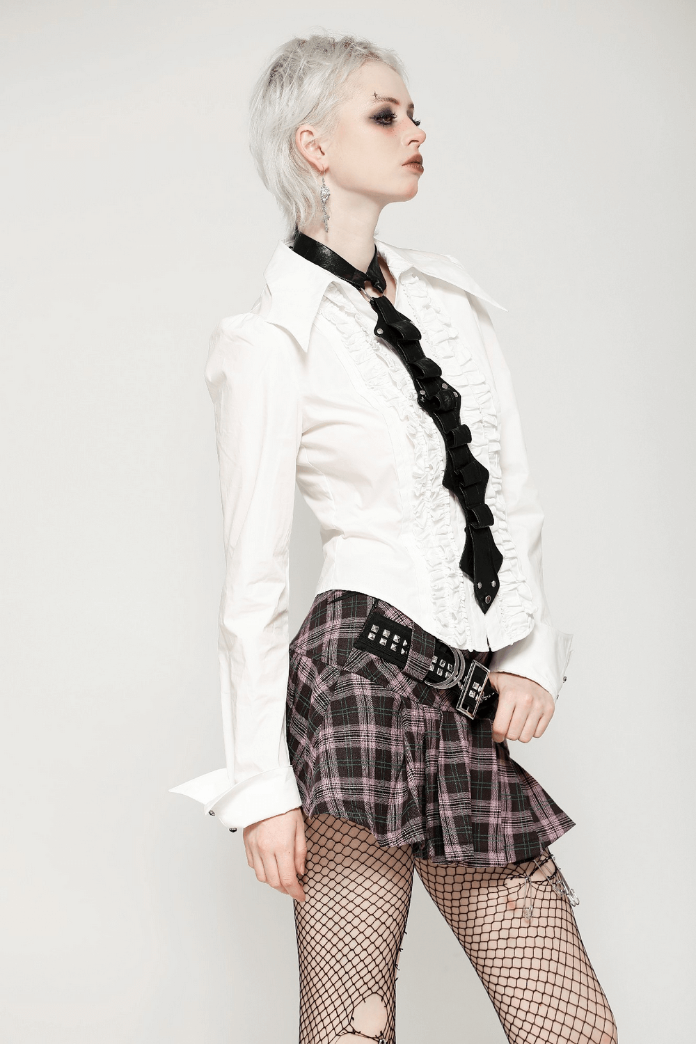 Trendy plaid mini skirt with studded belt, pleated design, and chic white ruffled blouse for edgy outfits.