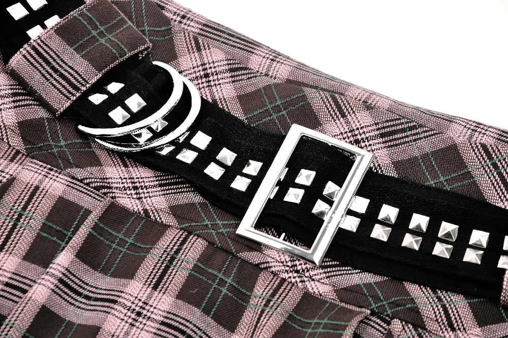 Close-up of plaid mini skirt featuring a studded belt and pleated design, showcasing the trendy black, pink, and green pattern.