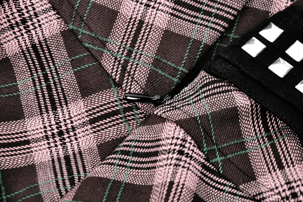Close-up of trendy plaid fabric featuring pink, black, and green pattern with studded belt detail on mini skirt.