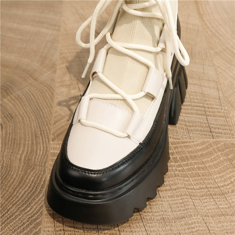 Close-up of stylish platform women's lace-up boots in white and black, featuring stretch fabric and chunky soles.