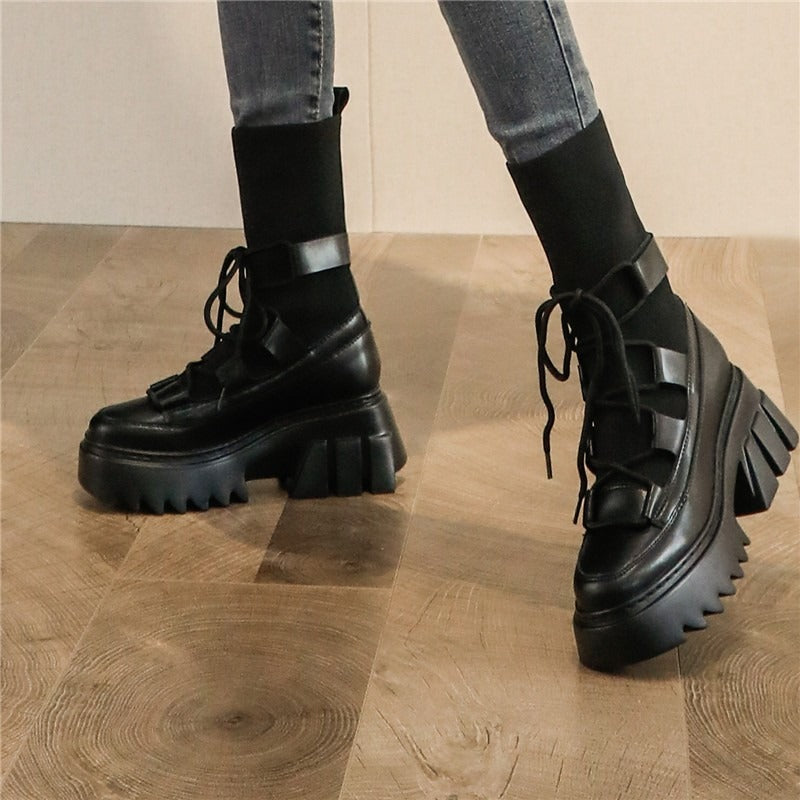 Platform women's lace-up boots in black with chunky soles, paired with skinny jeans on a wooden floor.