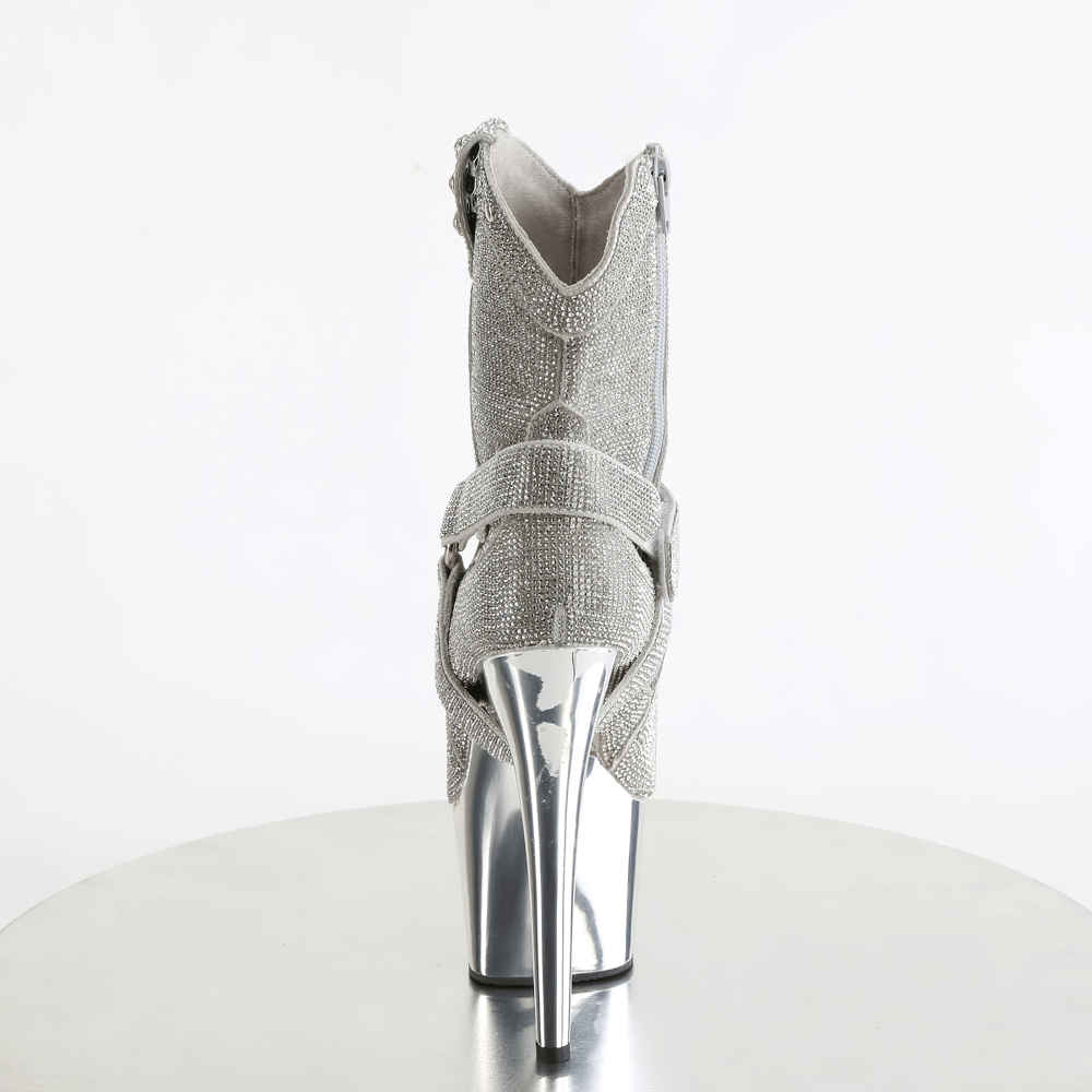 Back view of Pleaser silver rhinestone cowgirl boots with O-ring straps and shiny 7-inch heels on a table.