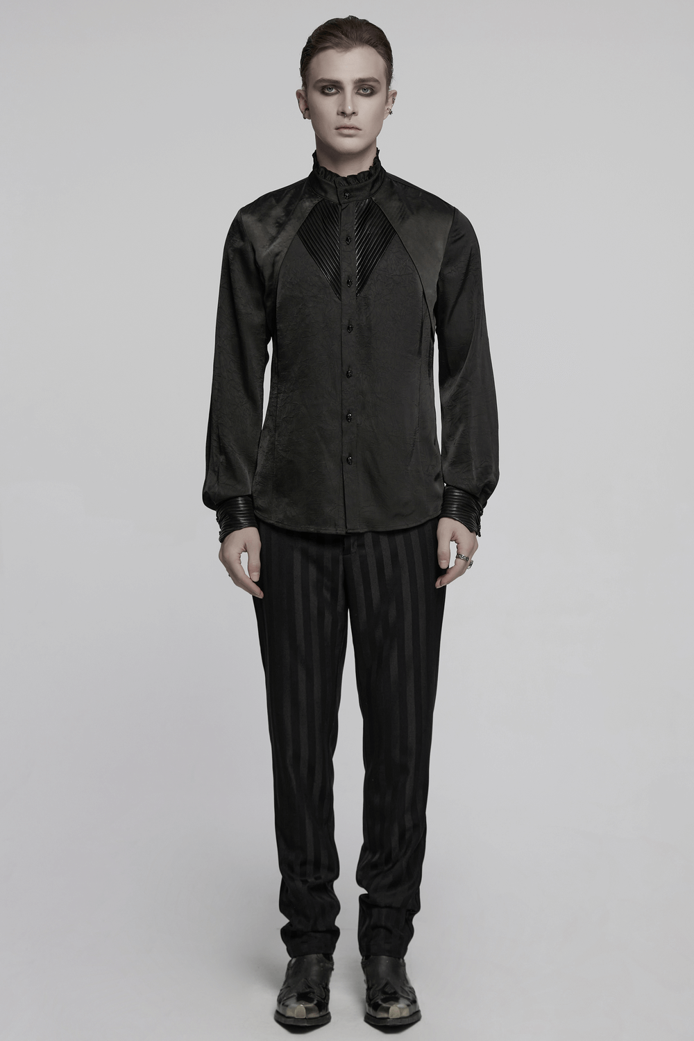 Model showcasing a Pleated Gothic Button-Up Shirt with glossy accents and structured design, paired with stripe trousers.