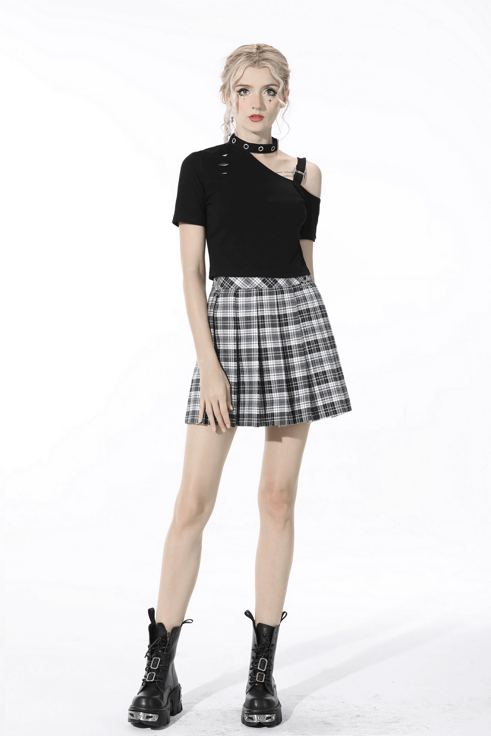 Model wearing pleated black and white plaid mini skirt with edgy black top and combat boots.