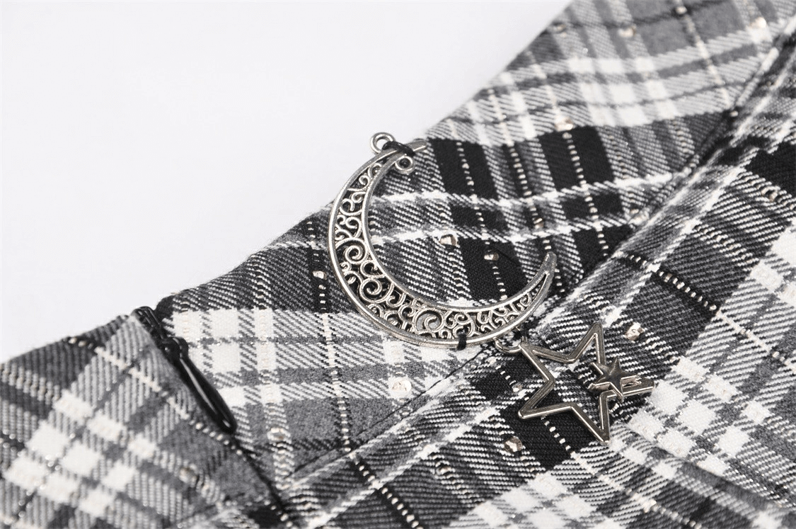 Close-up of pleated gothic mini skirt with black and white plaid and silver moon and star charms.