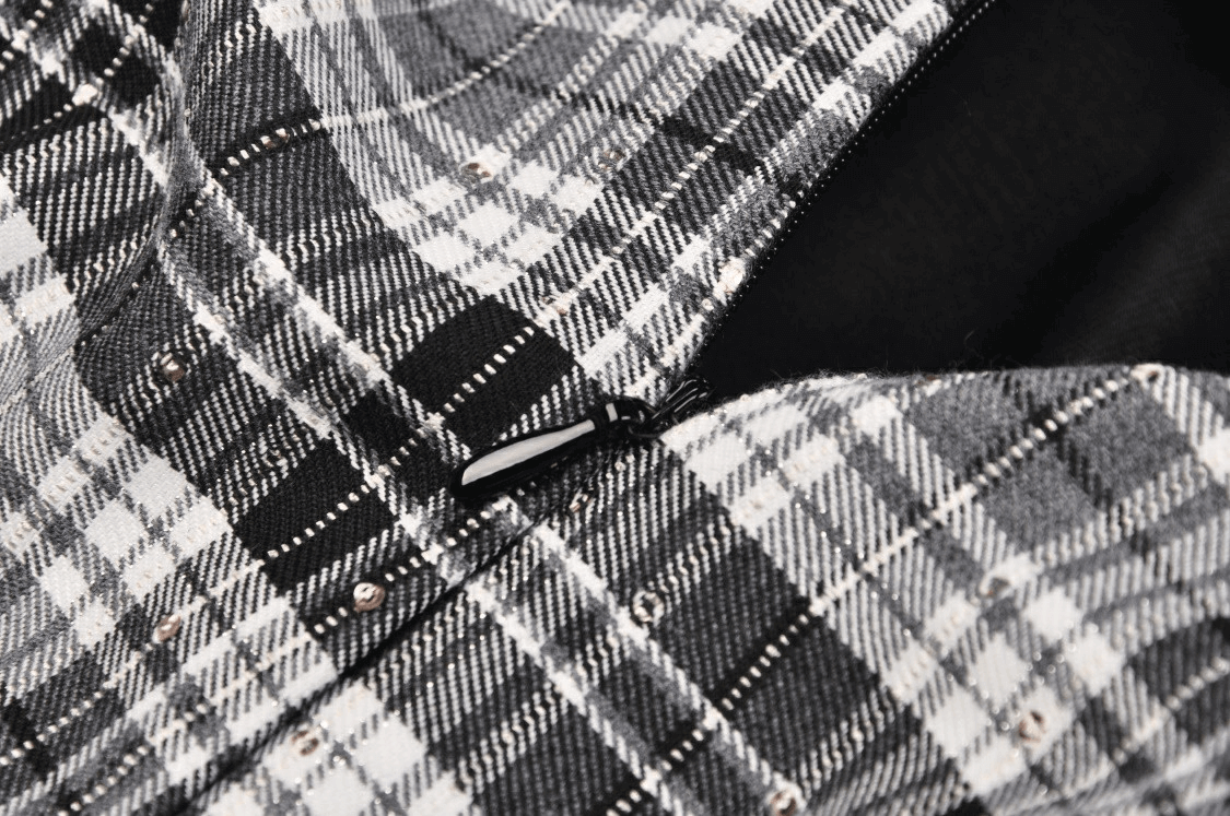 Close-up of a black and white plaid mini skirt showcasing pleats and zip detail, perfect for edgy grunge outfits.