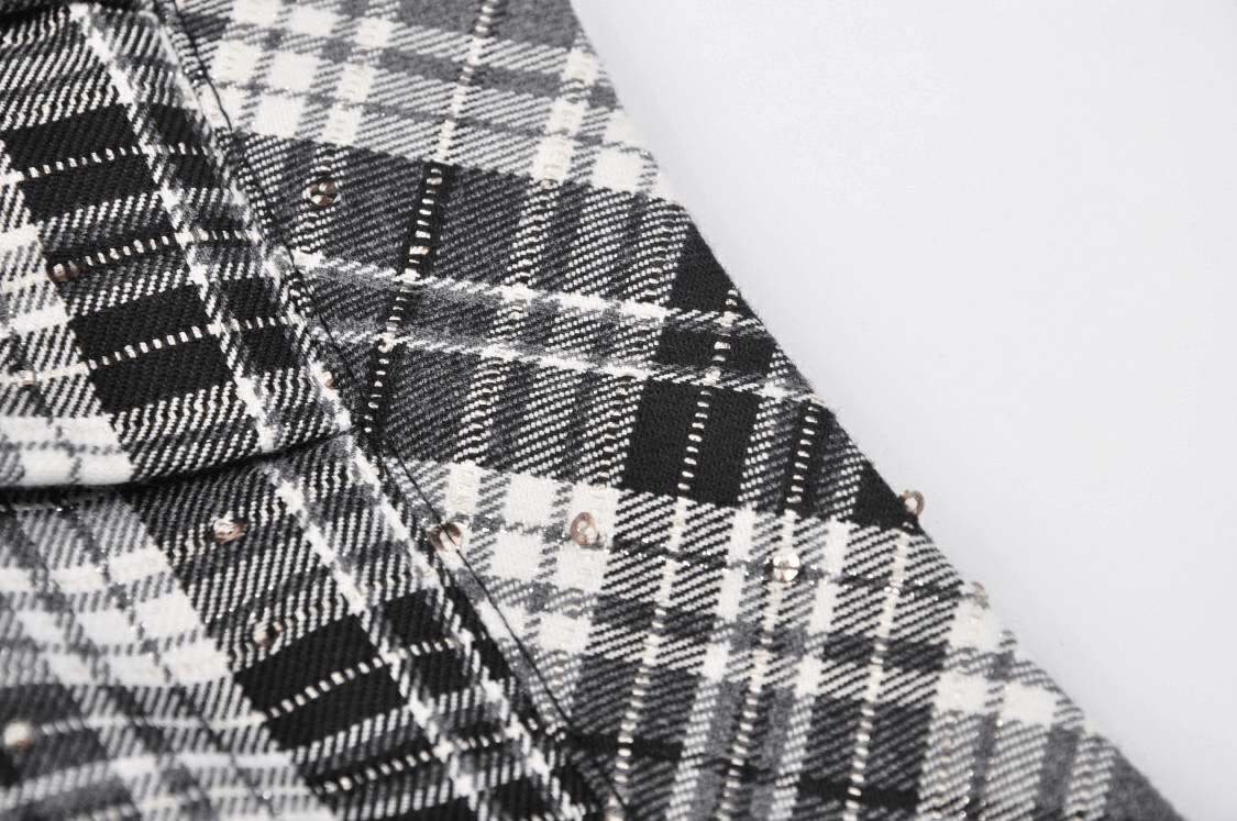 Close-up of pleated Gothic mini skirt in black and white plaid with edgy stud details.