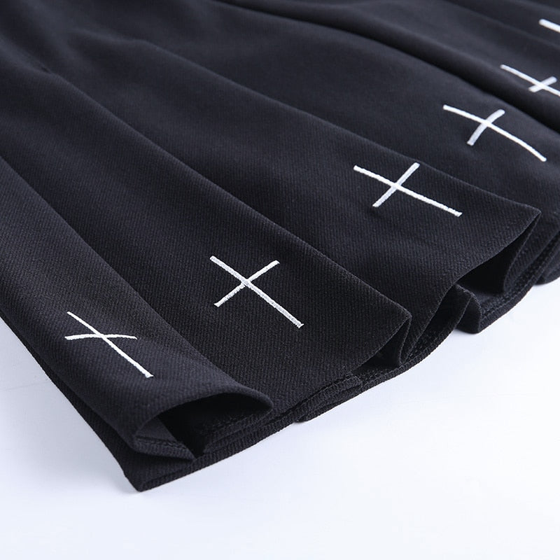Close-up of black pleated mini skirt with white cross decorations, perfect for gothic and rock chic style outfits.