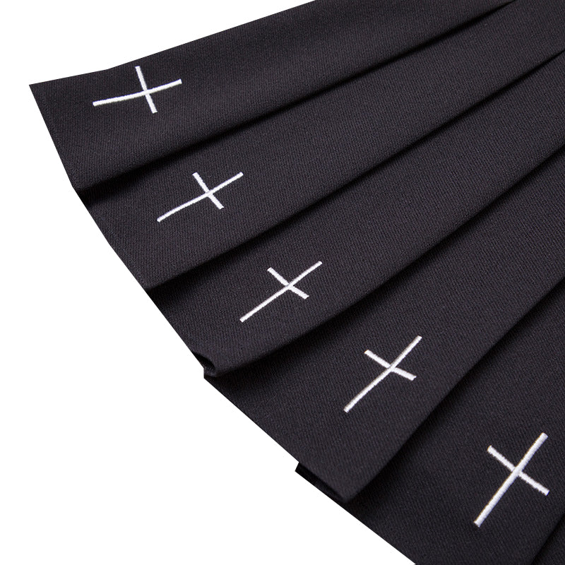 Close-up of pleated gothic women skirt featuring white crosses on a black fabric, perfect for alternative outfits and Halloween parties.