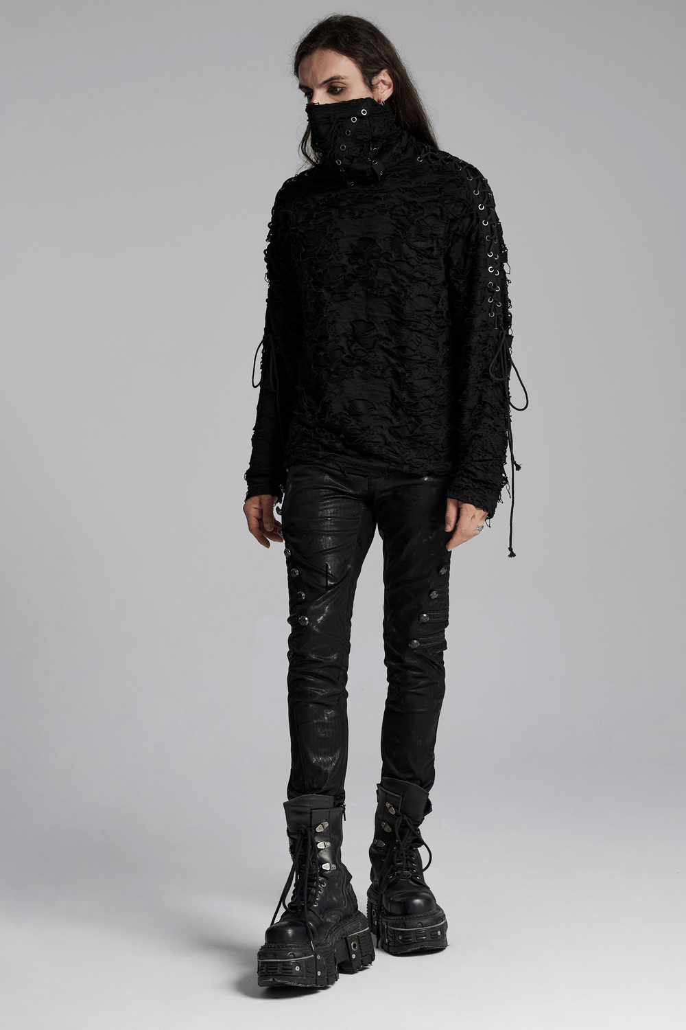 Model showcasing a post-apocalyptic distressed knit high-neck top with face mask, paired with edgy black pants and boots.