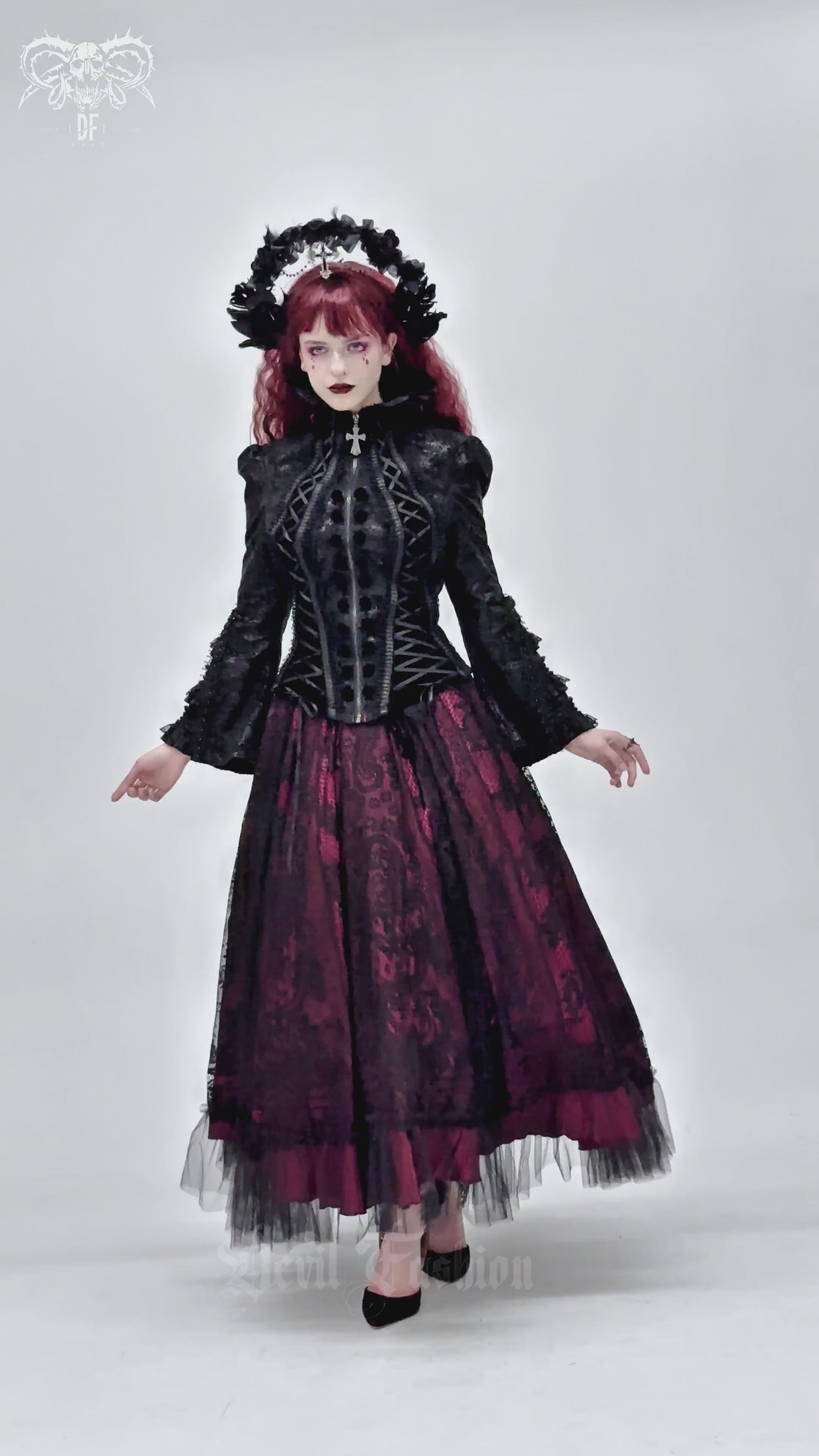 Gothic Lace-Up Victorian Jacket with Bell Sleeves and Cross worn over a flowing burgundy skirt in a dramatic pose.