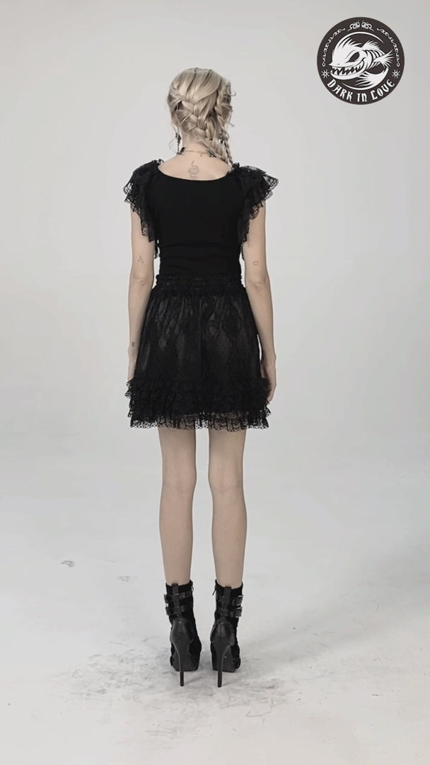 Back view of a woman in a gothic lace ruffled top and short black skirt, showcasing layered lace sleeves and stylish footwear.