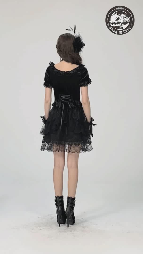 Back view of a gothic black velvet puff-sleeved top with lace-up detail and matching skirt, paired with stylish boots.