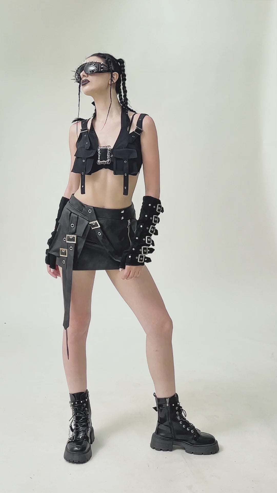 Model showcasing a black gothic crop top with buckles, paired with a stylish skirt and accessories.