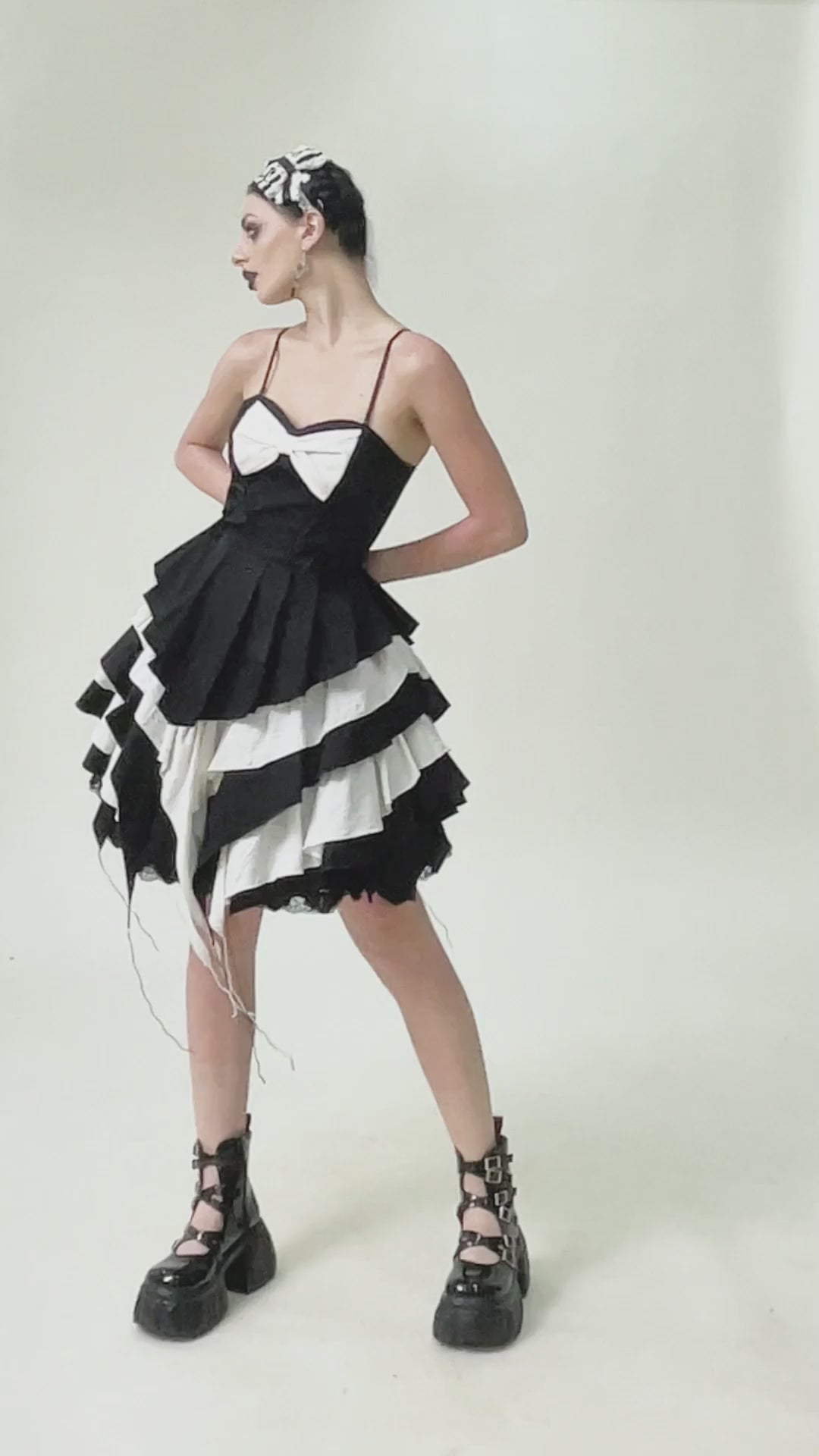 Model showcasing a black and white ruffled Gothic dress with lace and bow, perfect for alternative fashion.