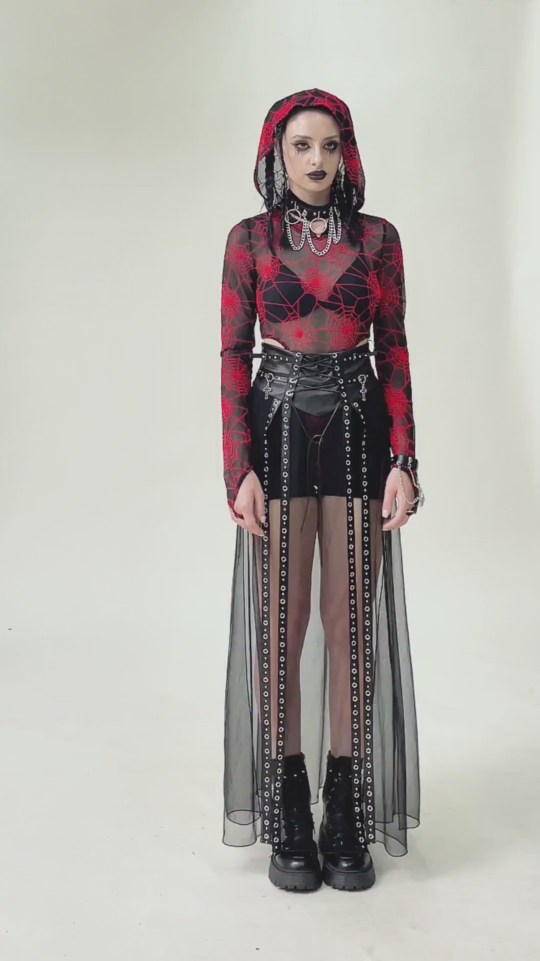 Gothic fashion model wearing a sheer black maxi skirt with stud details and a red floral top, showcasing edgy alternative style.