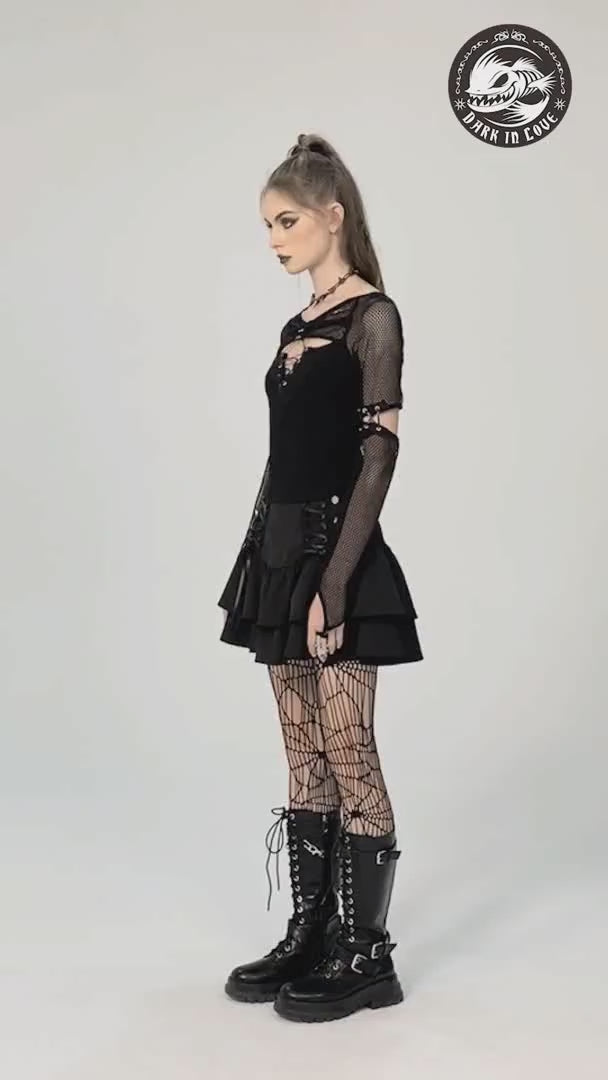 Model showcasing a dark goth layered mini skirt with lace-up details, fishnet tights, and combat boots in a stylish pose.