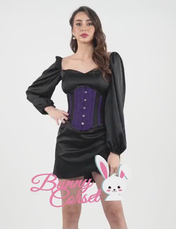 Elegant model in a black dress wearing a purple brocade waspie corset for a vintage-inspired look.