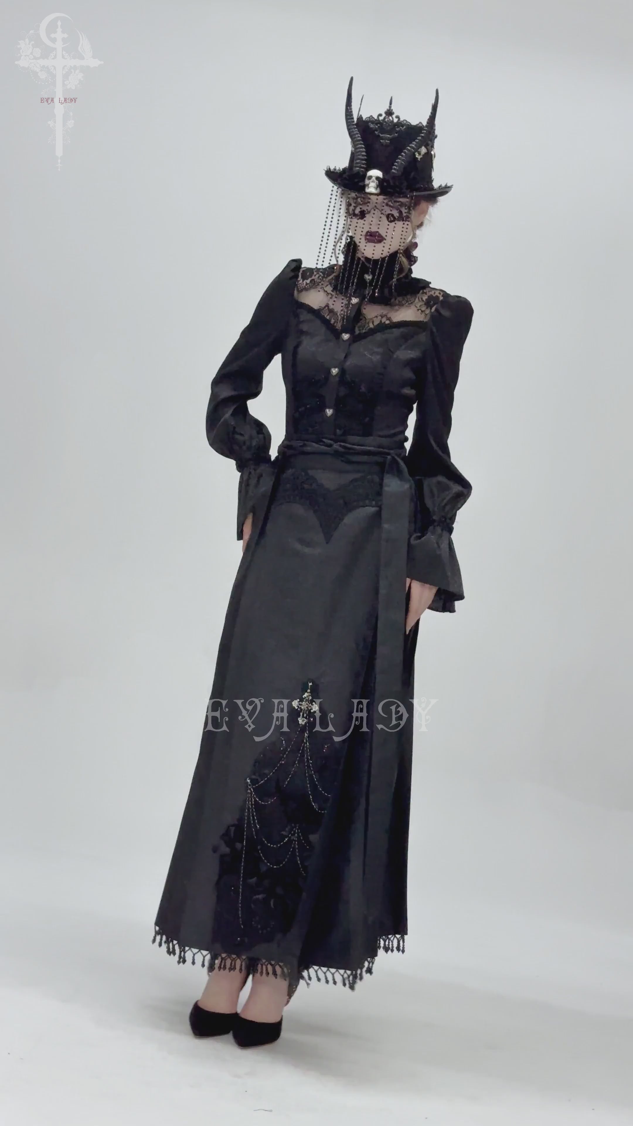 Gothic model in elegant black maxi dress with intricate lace and dramatic hat, showcasing dark Victorian fashion.