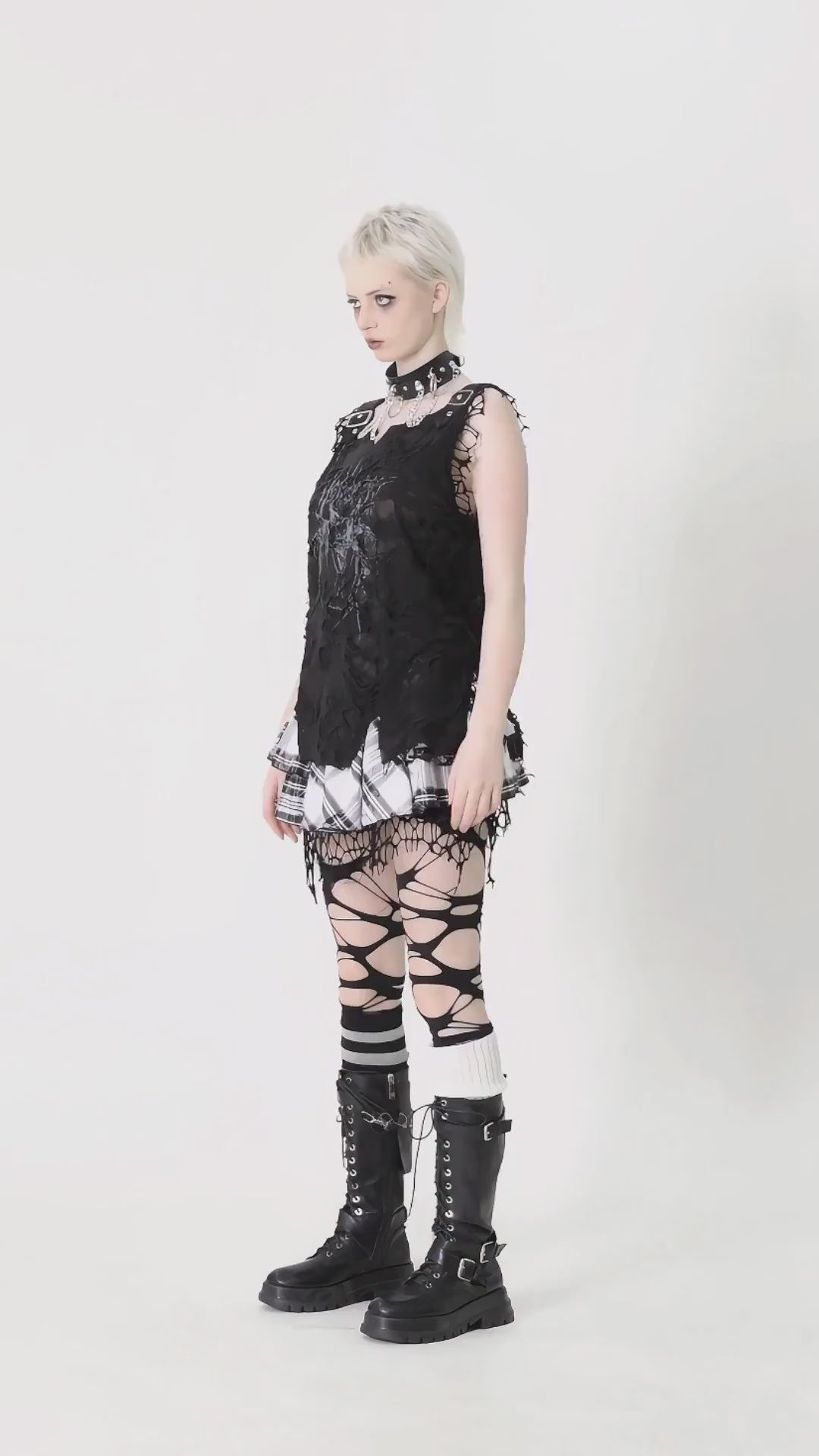 Model wearing a distressed black punk sleeveless top with lace details and ripped leggings, styled with combat boots.