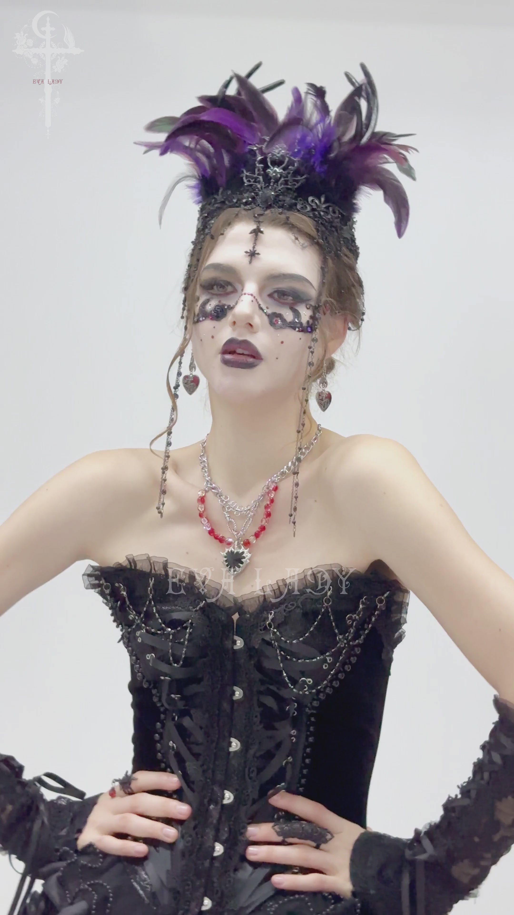 Gothic feathered headpiece worn by model, featuring purple and black feathers with chains and cross ornaments.